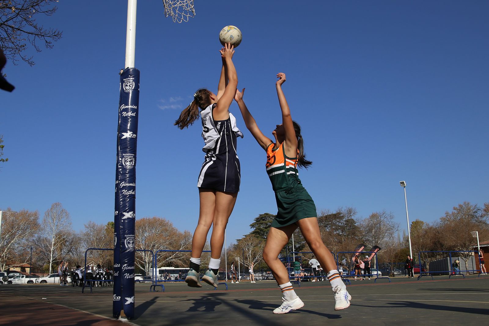 Netball shooter at the post under a blue sky